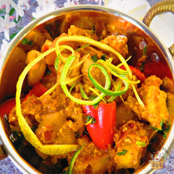 Rambutan Paneer topped with lime zest, peppers, and cilantro in a metal bowl