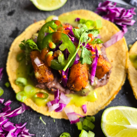 Crispy golden tostada topped with golden potatoes and colourful garnishes.