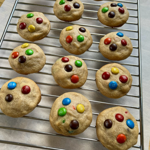 Peanut Butter M&M Cookies on a baking rack with some parchment paper underneath