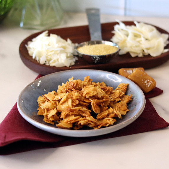 Sea salt caramel coconut chips in a small bowl on a burgundy napkin.