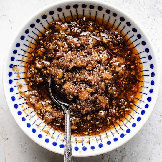 Shacha sauce in a white and blue bowl with stainless steel spoon
