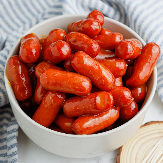 A bowl full of BBQ little smokies on a counter.