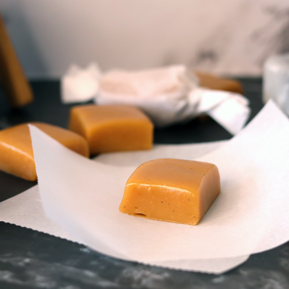 Soft creamy caramel candies in the process of being individually wrapped in parchment paper