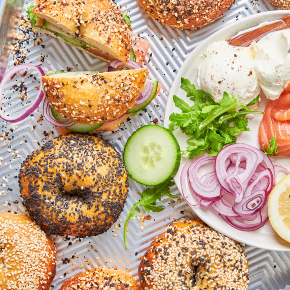 A tray of Sourdough Protein Bagels from above, a plate with salmon and cream cheese beside them