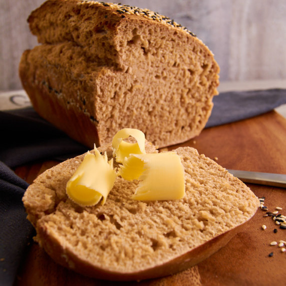 Sourdough wholewheat sandwhich bread, cut in half, a slice with butter curls in the front.