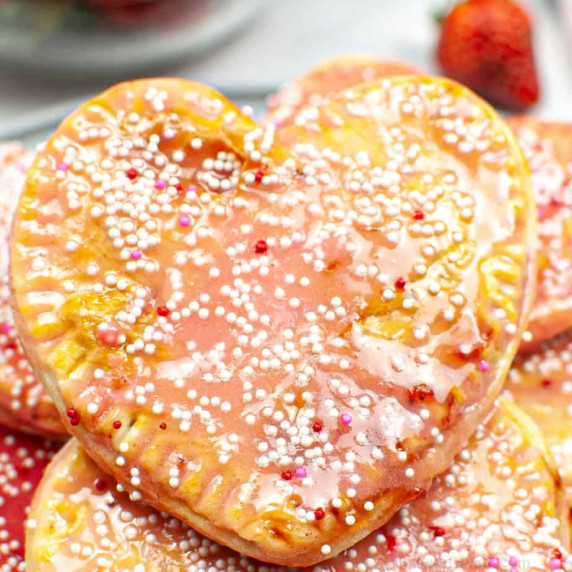 Close up of a heart shaped pop tart covered in a strawberry glaze and sprinkles.