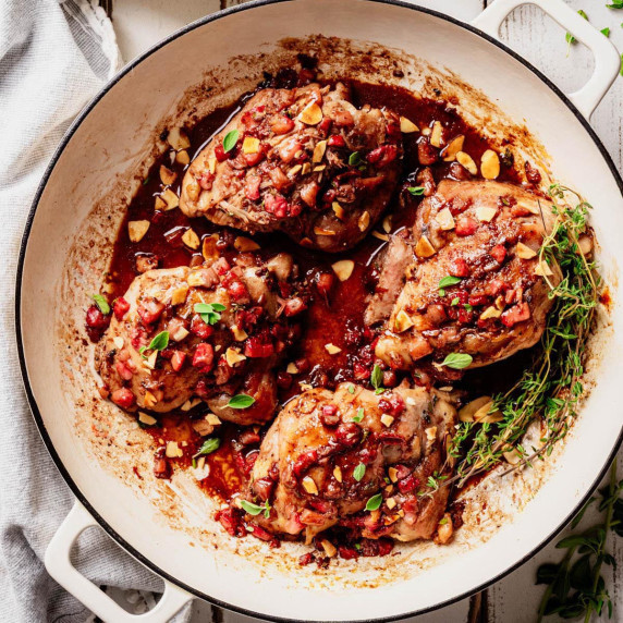 Skillet with chicken thighs topped with a chunky strawberry-balsamic glaze and toasted almonds