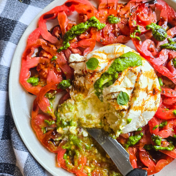 Red tomatoes, white burrata, green pesto, and black balsamic glaze