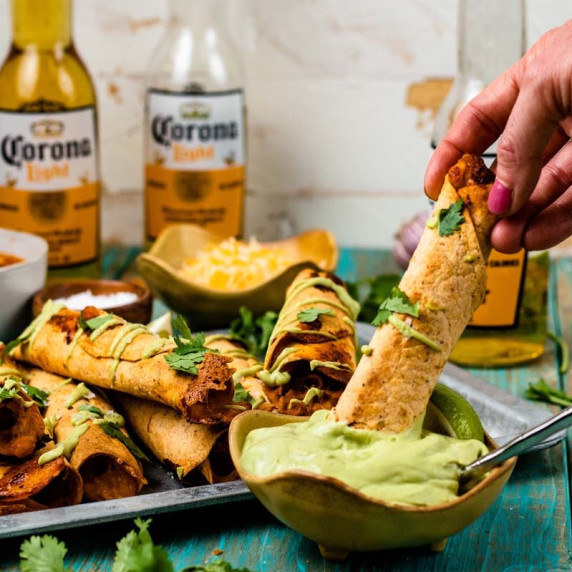 Chicken tinga taquitos dipped in avocado crema