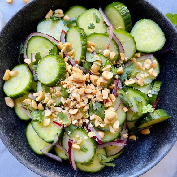 Cucumber and red onion slices in a vinegar dressing topped with chopped peanuts and cilantro.