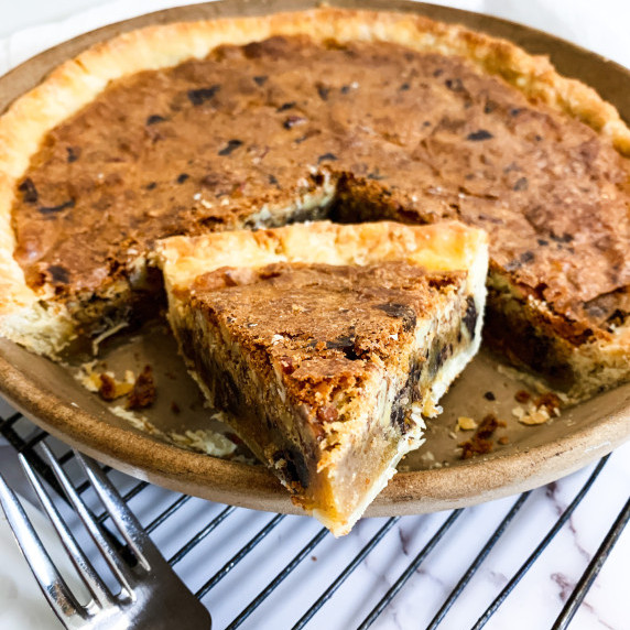 slice of tollhouse pie turned around in the pie plate to reveal gooey filling