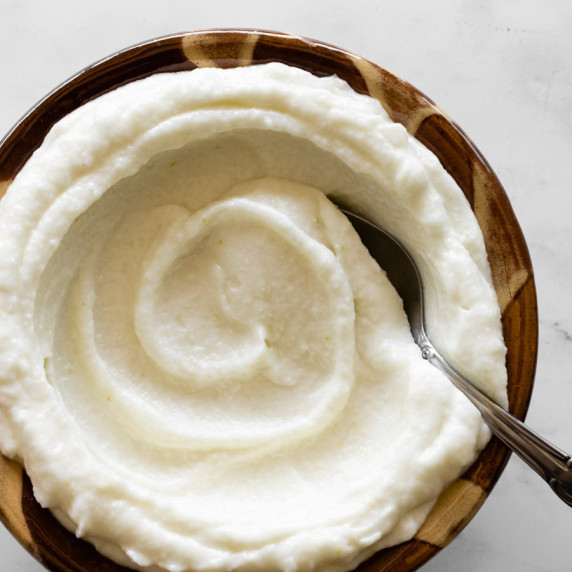 Toum swirled in a traditional Lebanese bowl with a spoon in the dip.