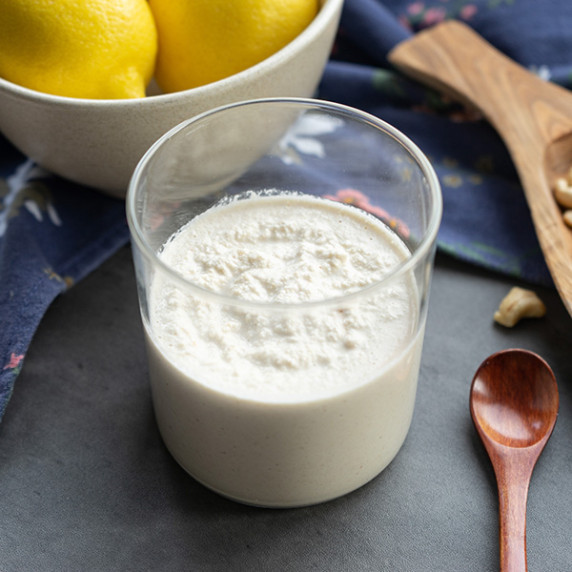 Vegan cashew cream in small jar with lemons salt and cashews