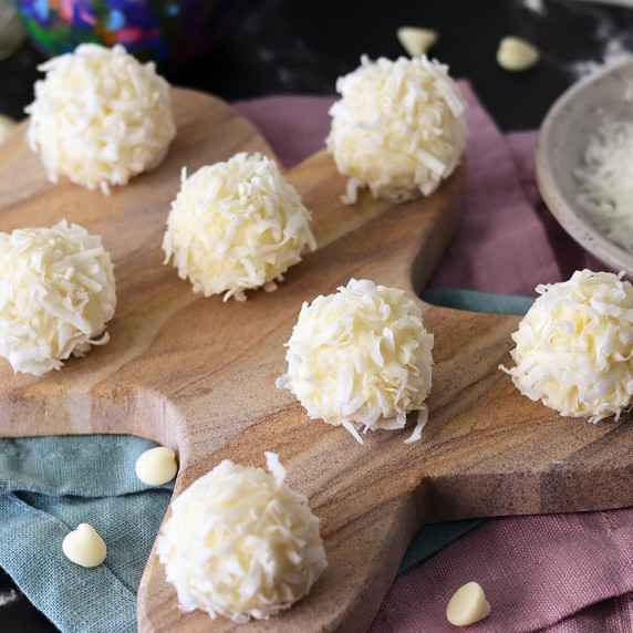 White chocolate coconut snowballs scattered on a gingerbread shaped board.