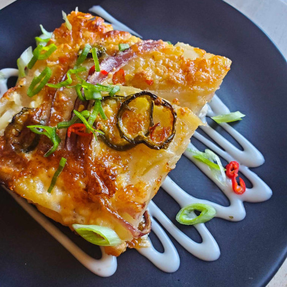 Golden brown potatoes, pops of green onion and red Thai chilis, and a white sour cream 