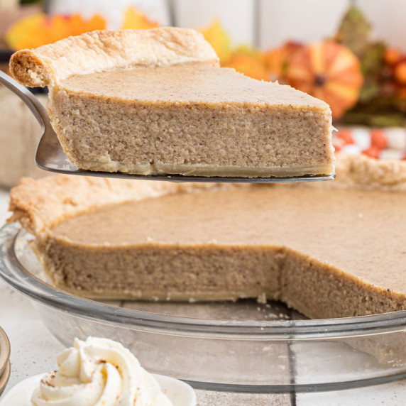 A slice of white pumpkin pie being lifted out of a pumpkin pie dish.