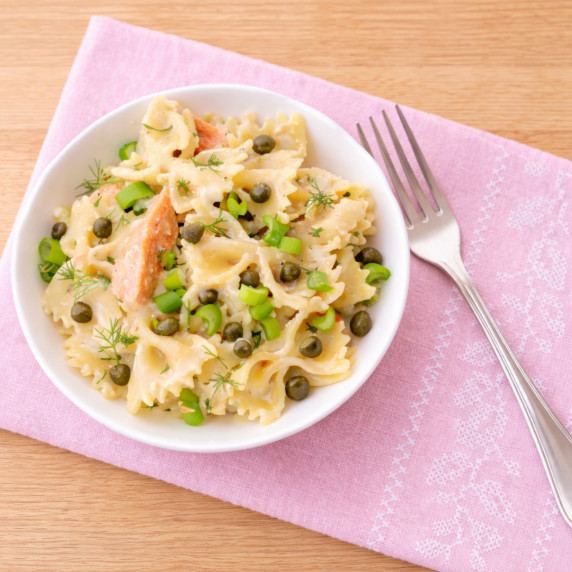Salmon farfalle pasta salad with capers, herbs, and green onions.
