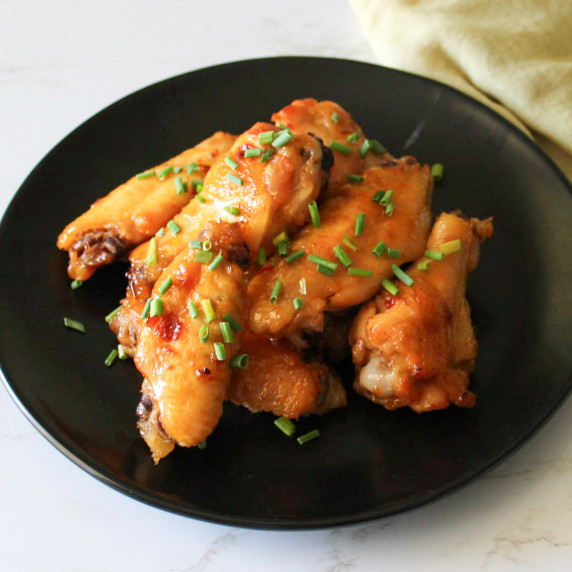 A plate of agave chili lime chicken wings garnished with chives