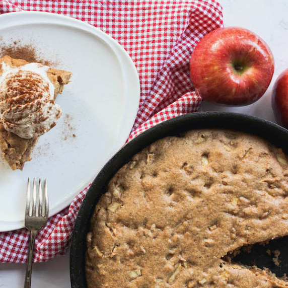 overhead image of apple cake in a skillet with slide on plate 