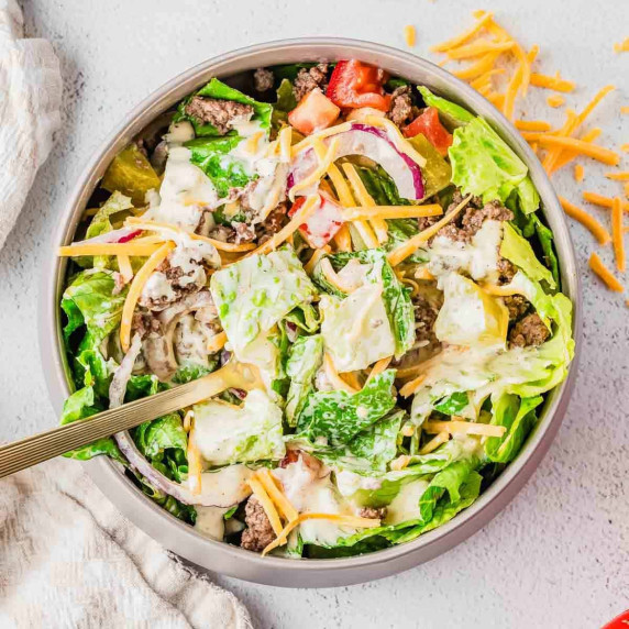 Big Mac salad with ground beef, lettuce, cheddar cheese, pickles, tomatoes, and creamy dressing.