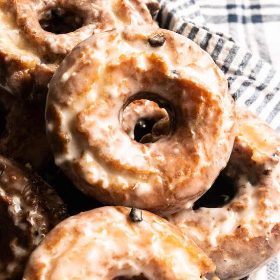 A pile of fried and glazed blueberry cake donuts.