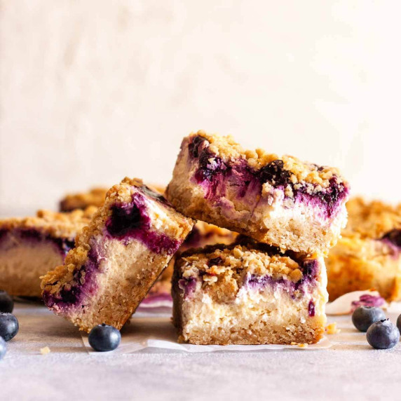 Blueberry cheesecake crumble bars on white parchment paper.