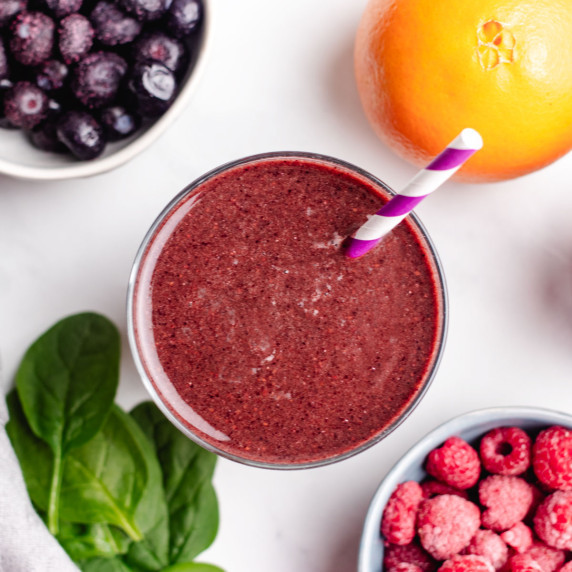 Blueberry and raspberry smoothie in a glass with a straw.
