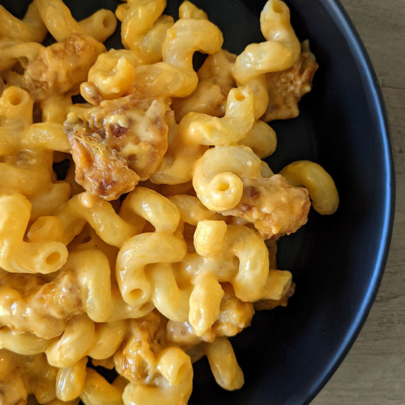 A bowl of creamy mac n cheese topped with crispy buffalo chicken nuggets