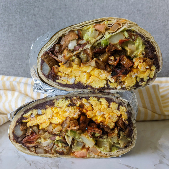 Two halves of a bacon egg and cheese breakfast burrito stacked