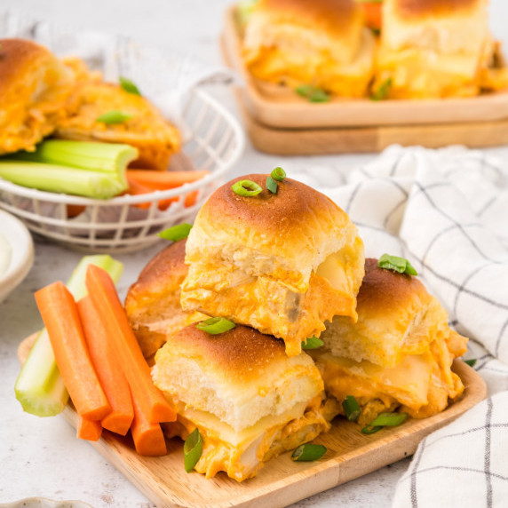 Buffalo Chicken Sliders served on a wood tray with carrots and celery.