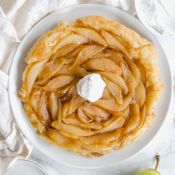 cardamom pear tart tatin on white plate and white marble background