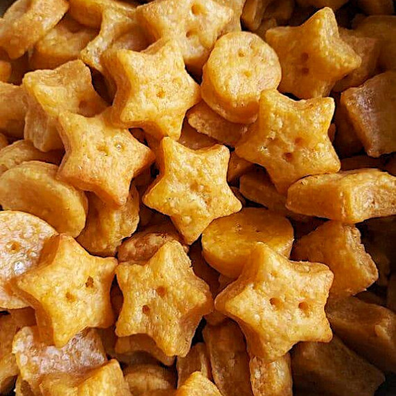 Extra close shot of orange coloured, cheesy stars and squares.