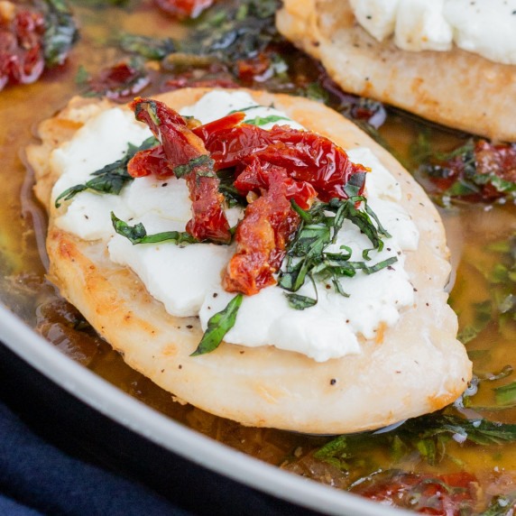 Chicken Bryan (Carrabba’s Copycat) RECIPE in a skillet garnished with sun dried tomatoes and greens.