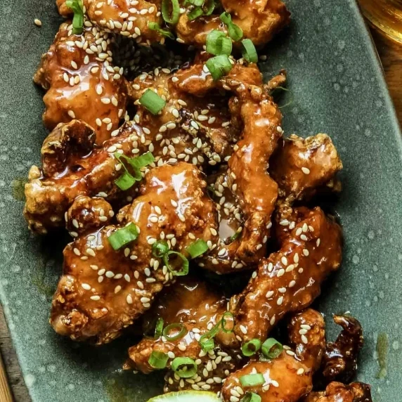 Closeup of Chinese lemon chicken in a sticky and tart lemon sauce on a green plate.