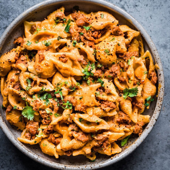 overhead photo of chipotle pasta with cilantro in a white bowl on a grey background