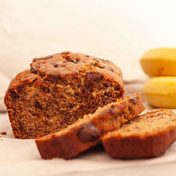 Sliced chocolate chunk banana bread on a white surface.
