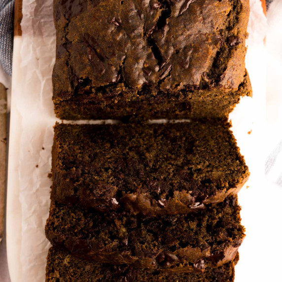 Chocolate chunk buckwheat banana bread half sliced on a parchment paper.