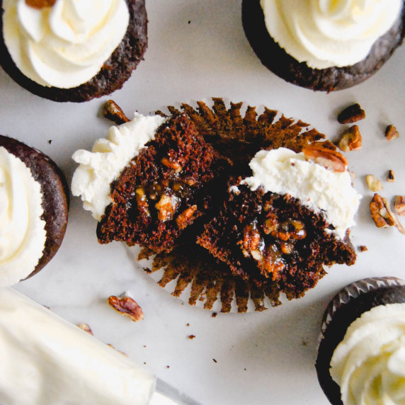 chocolate pecan pie cupcake cut in half to show the filling on marble background with piping bag