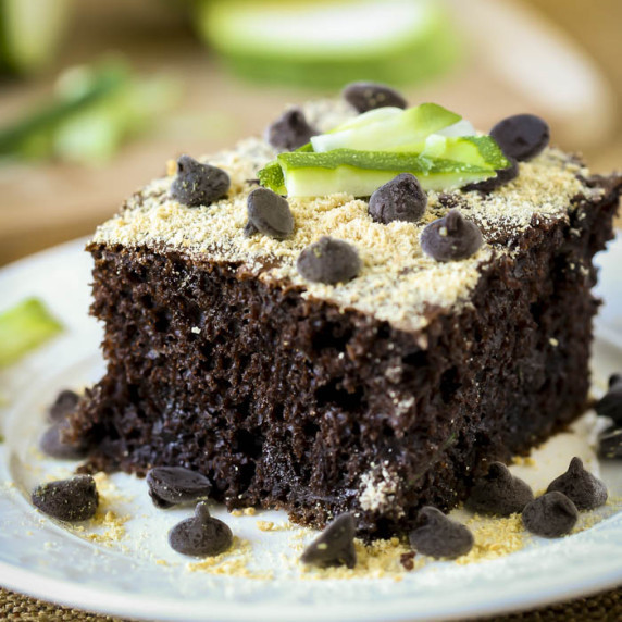 Side close up shot of a piece of zucchini cake garnished with chocolate chips and zucchini.