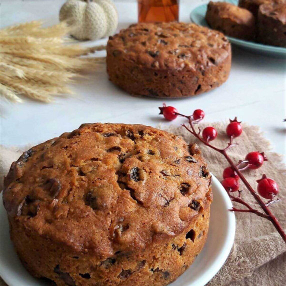 Close image of a deep brown British Christmas cake, with a smaller one in the background.