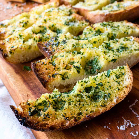 long rectangles of garlic bread on wooden board.