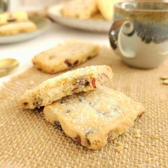 Extra close shot on ehssian material, of 2 square shaped, cranberry orange pecan Scottish shortbread