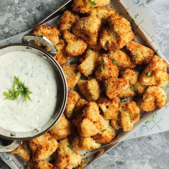 Crispy cauliflower bites on a silver tray with homemade buttermilk ranch in a silver bowl.