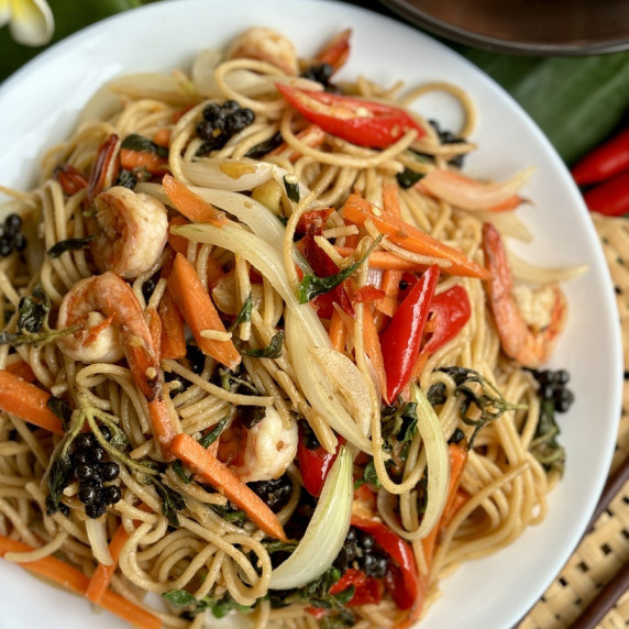 Thai spaghetti kee mao, drunken noodles, served in a white dish.