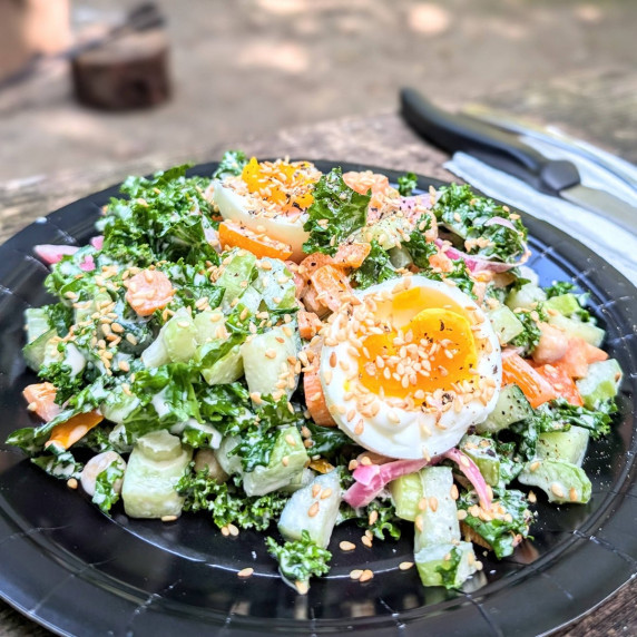 Make-ahead camping power salad with kale, chickpeas, and egg on a camping picnic table