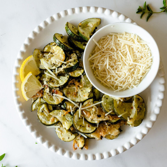 sliced roasted zucchini on a white plate topped with cheese.