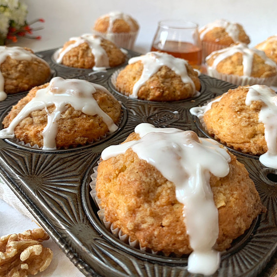 A muffin tin with iced mapled muffins.