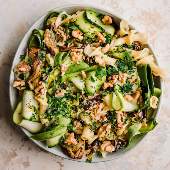 eggplant pasta in a white bowl on a white countertop.