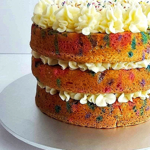 Extra close up shot of side of a funfetti (sprinkle) layer cake with buttercream fillign & topping.