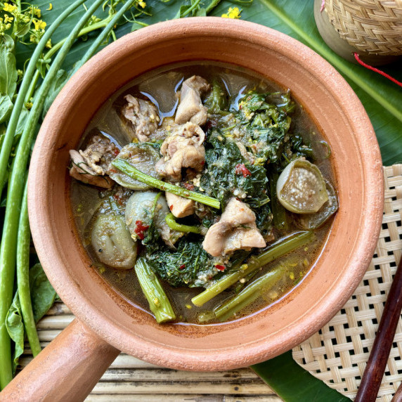Top-view of gaeng om gai, a Thai chicken soup or curry in a clay dish.